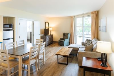 Dining set by a sofa and coffee table near large windows in Queen Cottage Water View at Rodd Brudenell River Resort