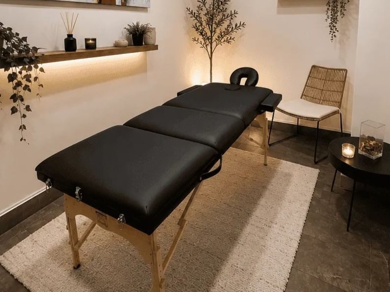 Sala de tratamiento del spa con camilla de masaje profesional y elegante arte en estantes de pared en Veranda Hotel