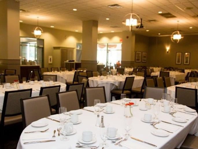 Asher\’s Dining Room set with multiple round tables and white linens at Spencer Hotel & Conference Centre