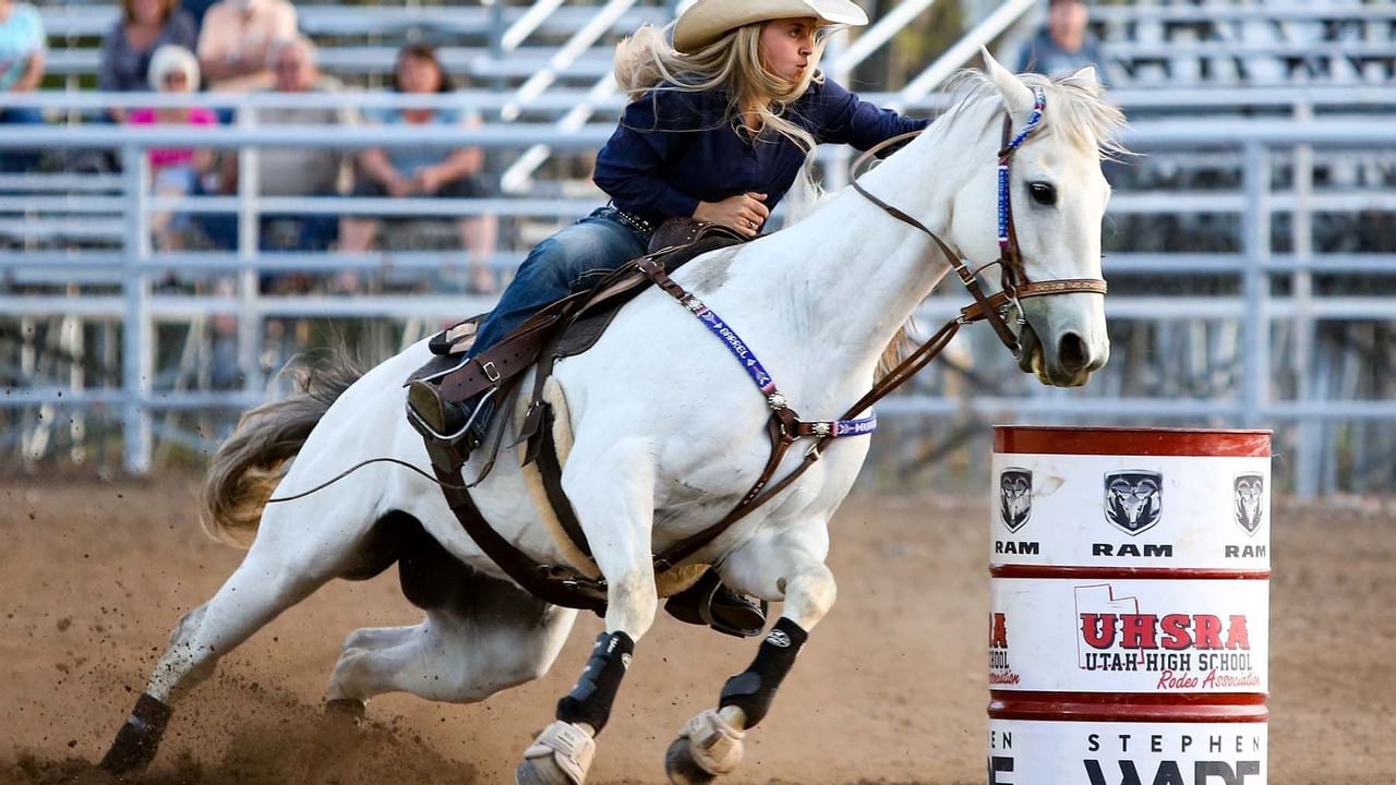 Woman with cowboy hat riding a horse during a rodeo