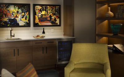 A mini bar area in Cosmopolitan at The Paramount Hotel Seattle with a wine cooler, a sink and two framed artworks
