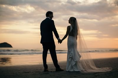 Newly wedded couple holding hands on the beach at sunset near Jungle Vista Boutique Hotel