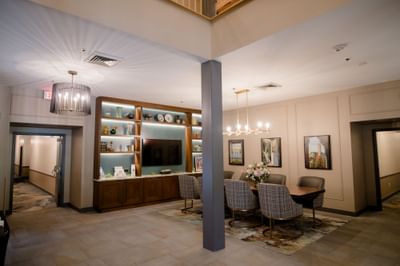 Spacious lobby dining area with long wooden table facing media wall and shelving unit at La Tourelle Hotel and Spa