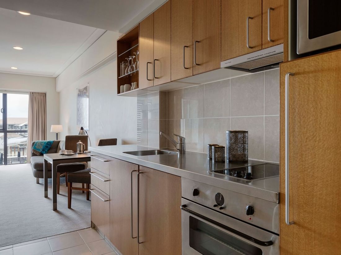 Marina View One Bedroom Suite kitchen with wooden cabinets and stainless steel appliances at Sebel Auckland Viaduct Harbour