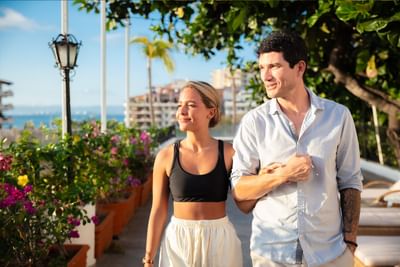 Couple walking arm in arm through tropical garden terrace with ocean views at Casa Dona Susana