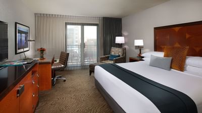 Cozy bed, workspace & lounge area in King Balcony Park View at Paramount Hotel Portland