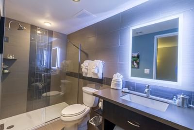 A stylish bathroom with a walk-in glass shower, a modern sink, and an illuminated mirror in a room at The Stanley Hotel