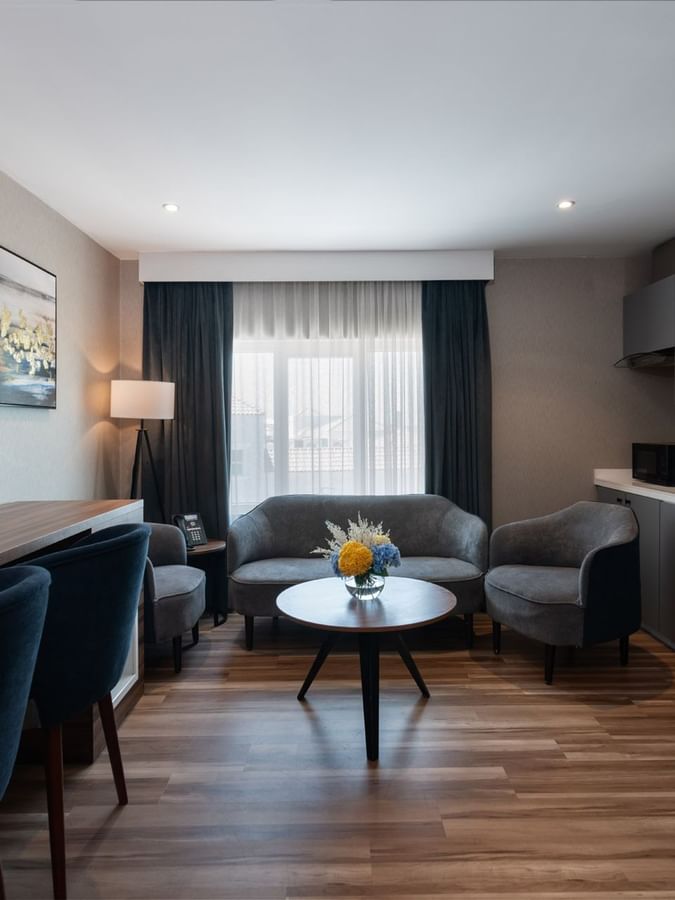 Grey sofa and chairs by a round coffee table and a kitchenette area in Junior Suite Sea View at Warwick Al Jubail