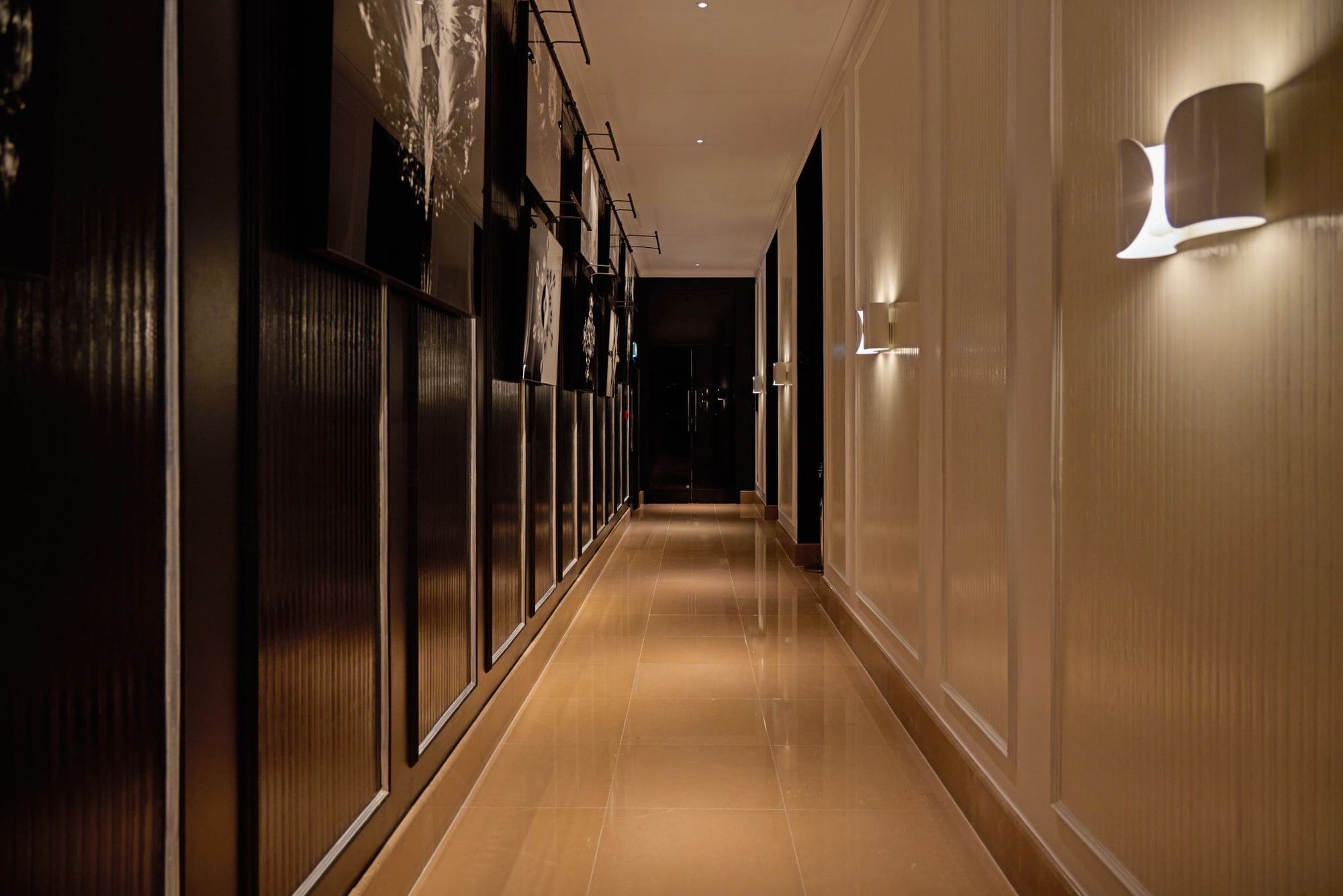 A long, illuminated hallway with modern wall sconces at The May Fair Hotel, London.