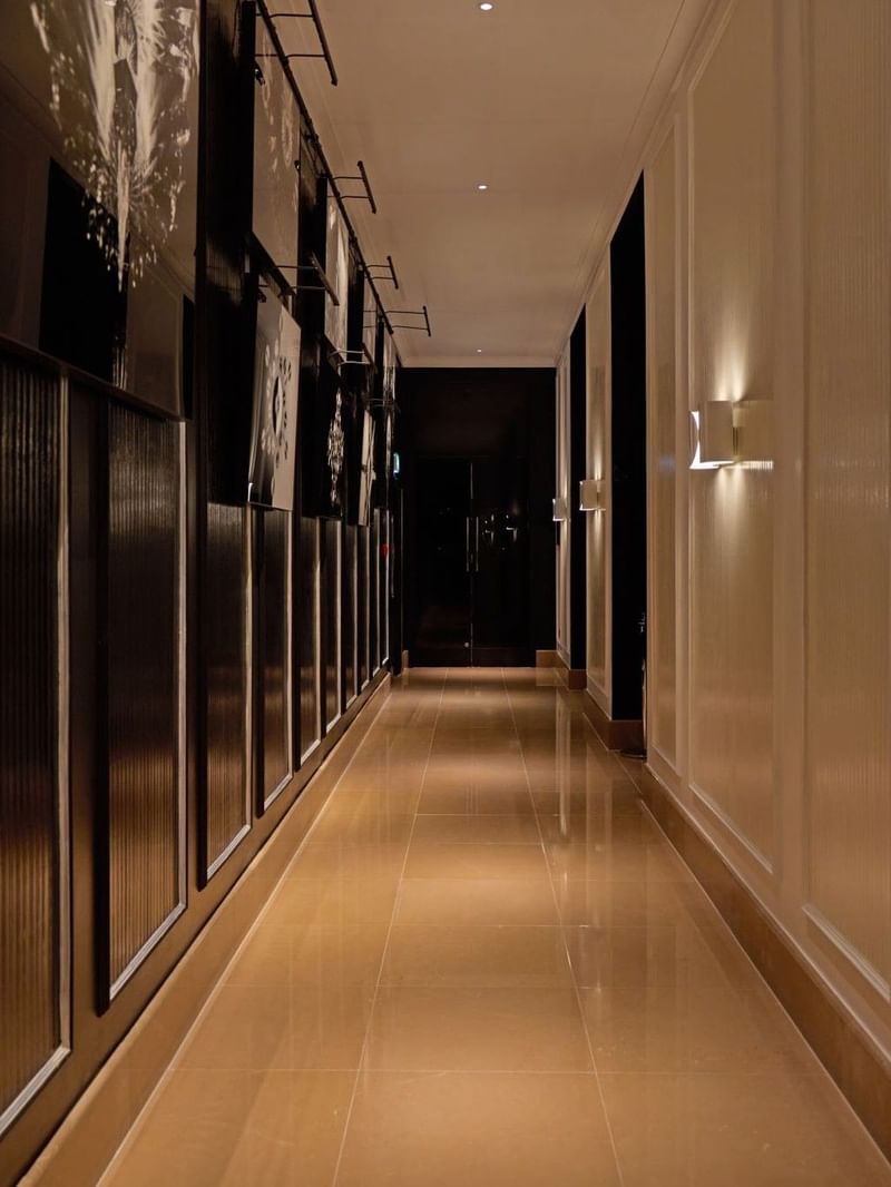 A long, illuminated hallway with modern wall sconces at The May Fair Hotel, London.