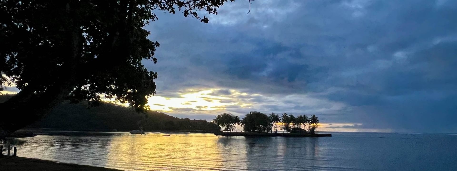 Sunset over tranquil waters with palm trees at The Naviti Resort in Korolevu, Fiji