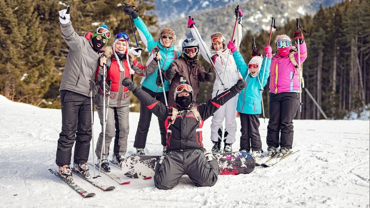 Group of skiers and snowboarders celebrating together on a snowy slope at Apex Mountain Resort near Coast Penticton Hotel