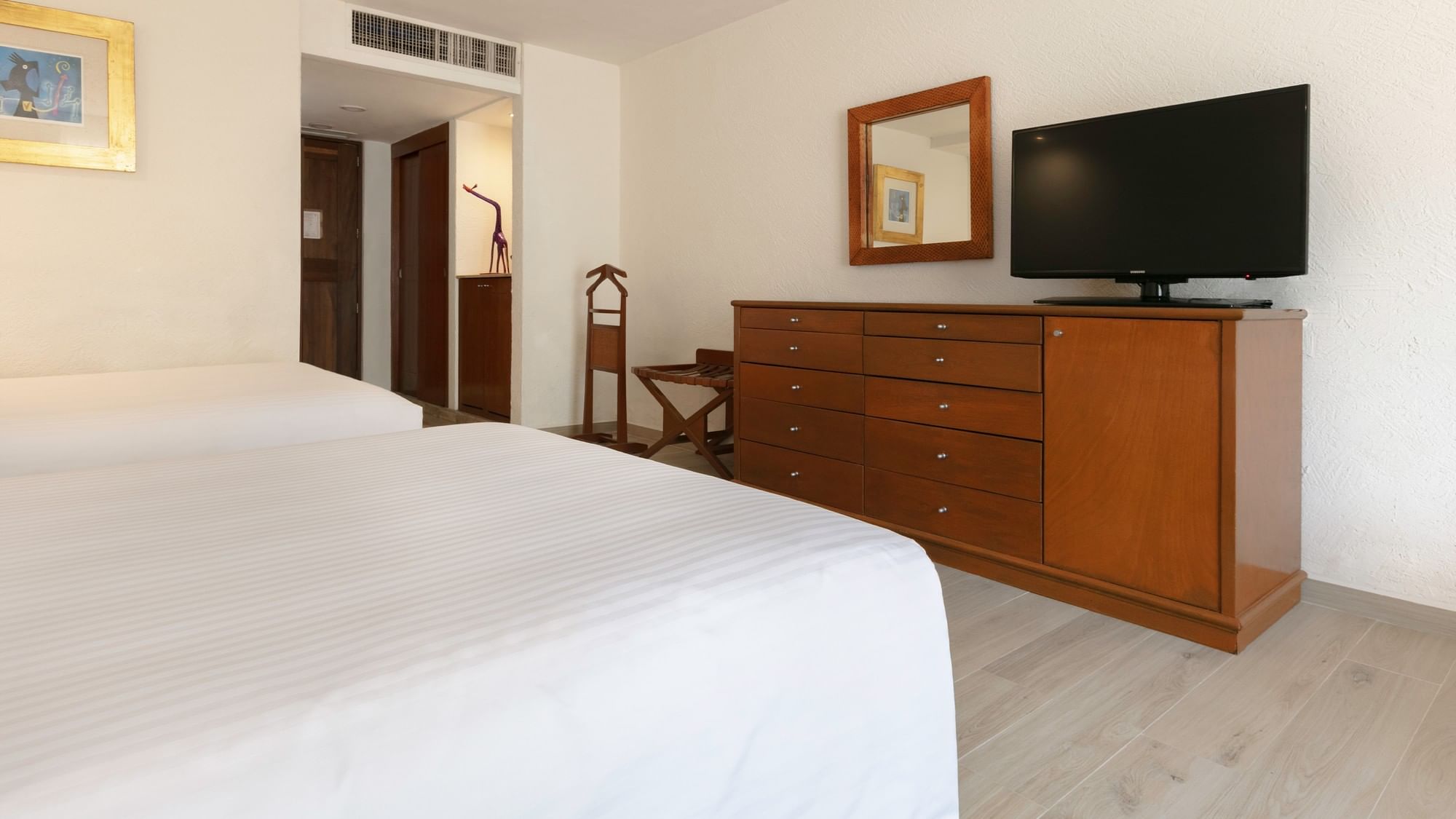 Two double beds in a hotel room with dresser and TV at Camino Real Guadalajara in Zapopan