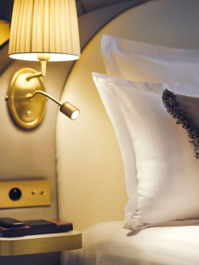 Bedside lamp and outlet panel on a wall, positioned by pillows on a bed in Superior Single Room at Hotel Westminster Paris