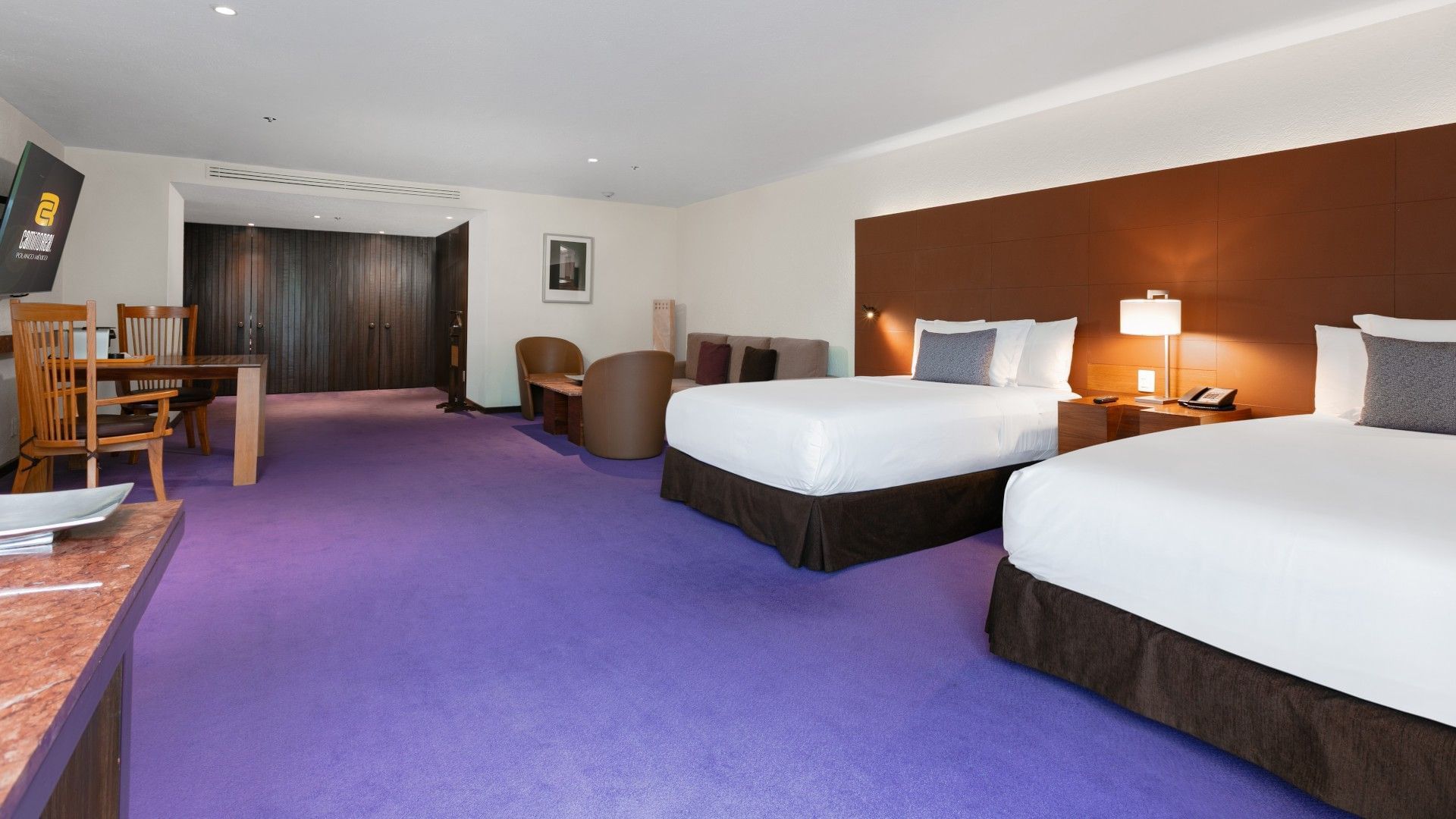 2 Double Junior Suite featuring vibrant purple carpet and a cozy seating area at Camino Real Polanco Mexico