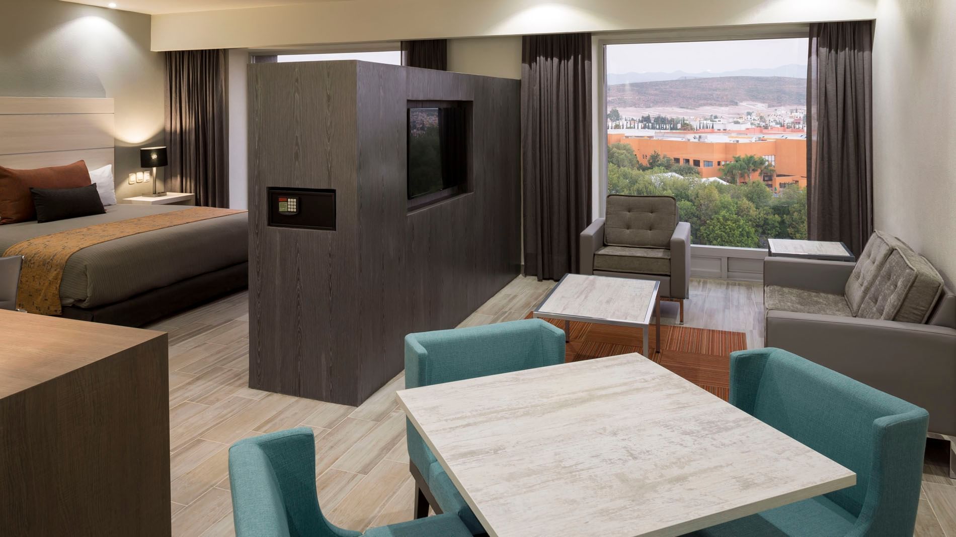 Dining table by the TV lounge area with city views in the King Junior Suite at Real Inn San Luis Potosi