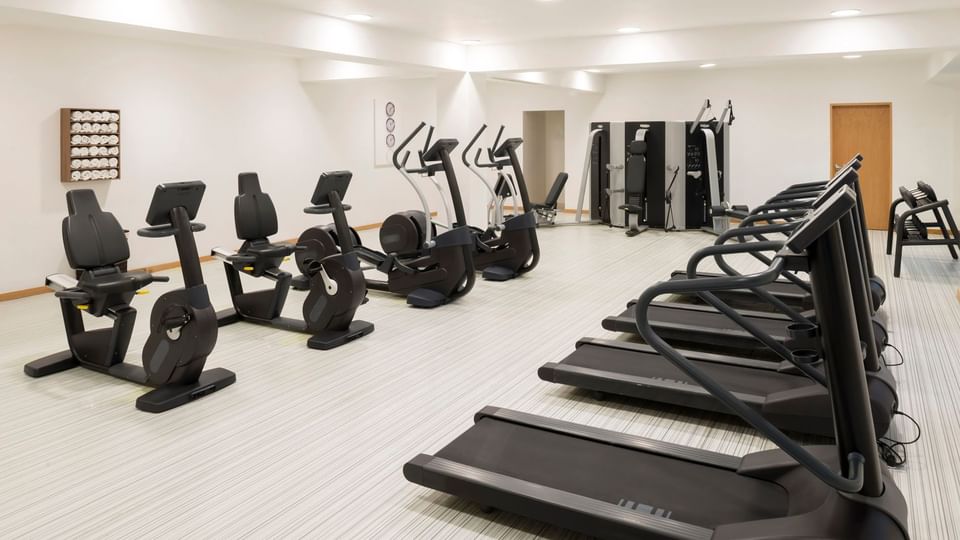 Exercise bikes by treadmills under bright lights surrounding a clean workout space in the gym at Real Inn Mexicali