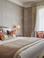 Deluxe Suite Belle Époque featuring a bed under a wall lamp and a couch near window at Hotel Westminster Paris
