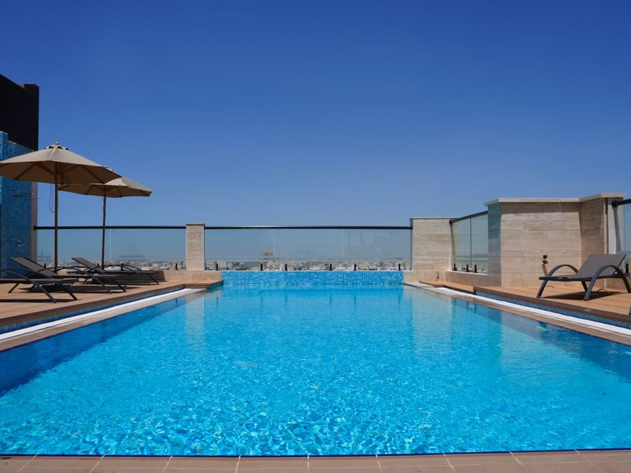 Rooftop pool and lounge chairs with umbrellas at Senses Spa, Warwick Hotel & Spa - Jeddah.