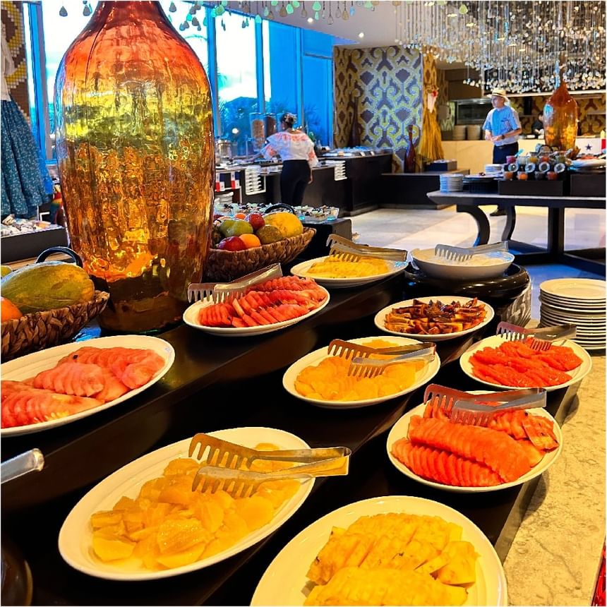 Bufé de desayuno con papaya, piña y melón cortados en mostradores negros de varios niveles en Megapolis Hotel Panama