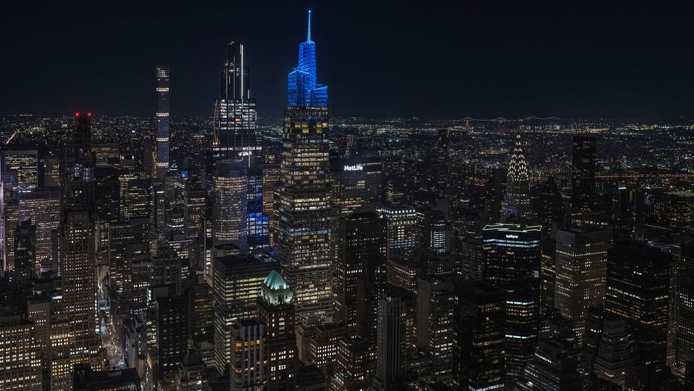Illuminated skyline with blue-lit skyscraper at night in New York City.