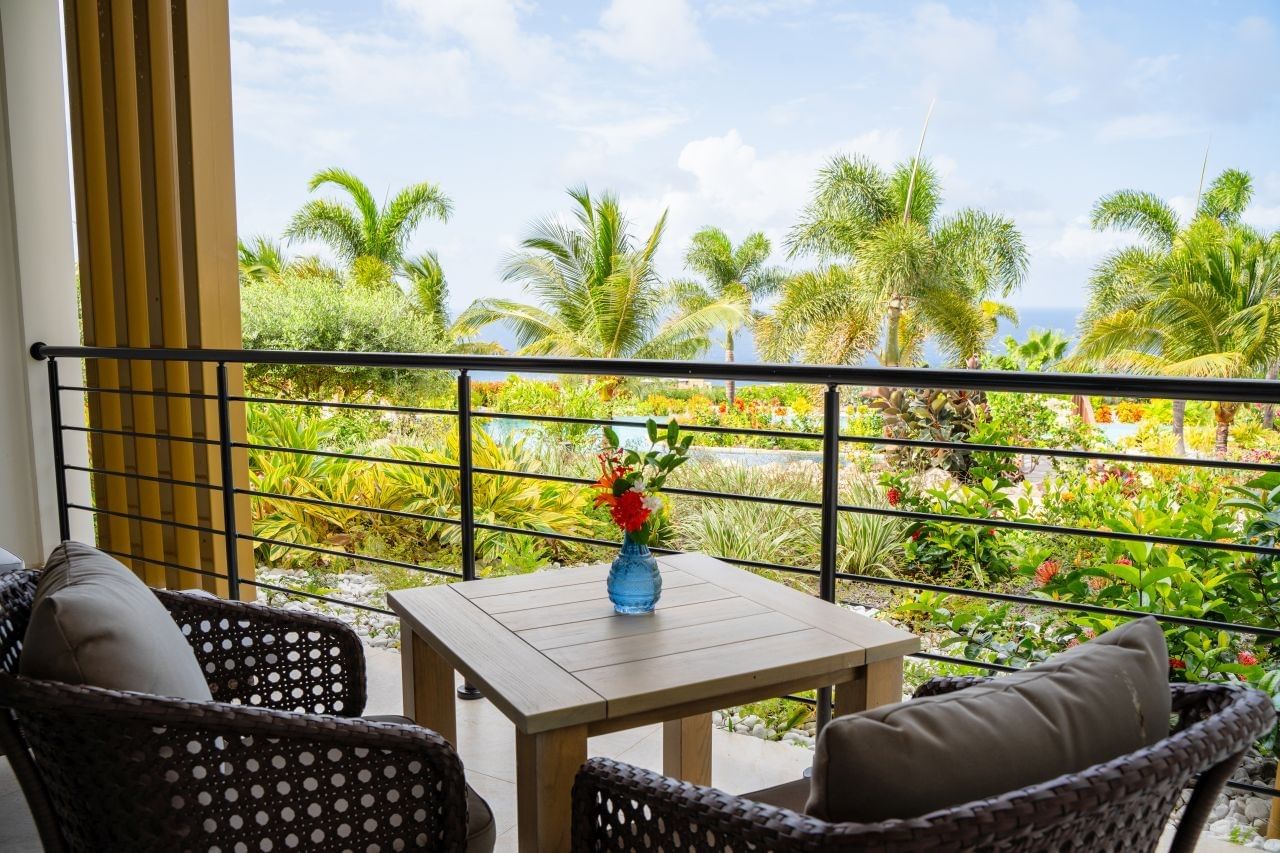 Private balcony seating area featuring a wooden table and comfortable armchairs overlooking the garden at Golden Rock Resort