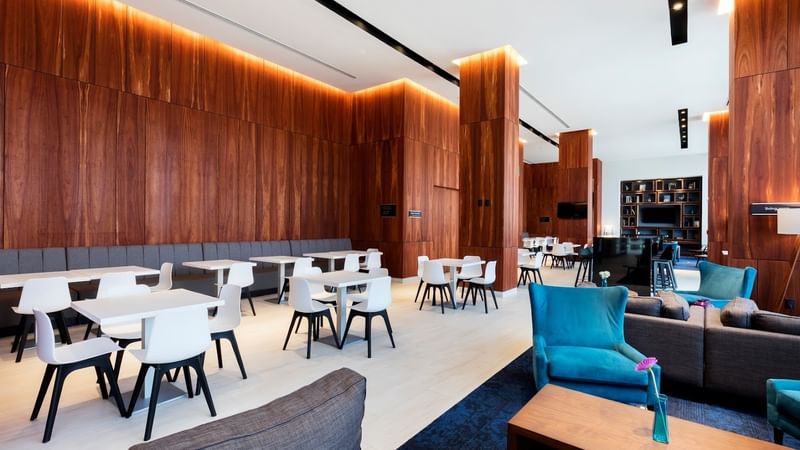 15 comedor 3 at Fiesta Inn Express Cancún Cumbres with a blue armchair and wood-paneled wall, Cancun Mexico restaurant