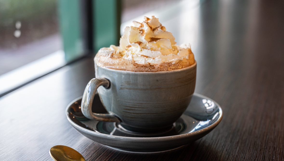 A pale blue mug of hot chocolate topped with whipped cream and cocoa powder, found at the Chocolate Museum and Café in Orlando. 