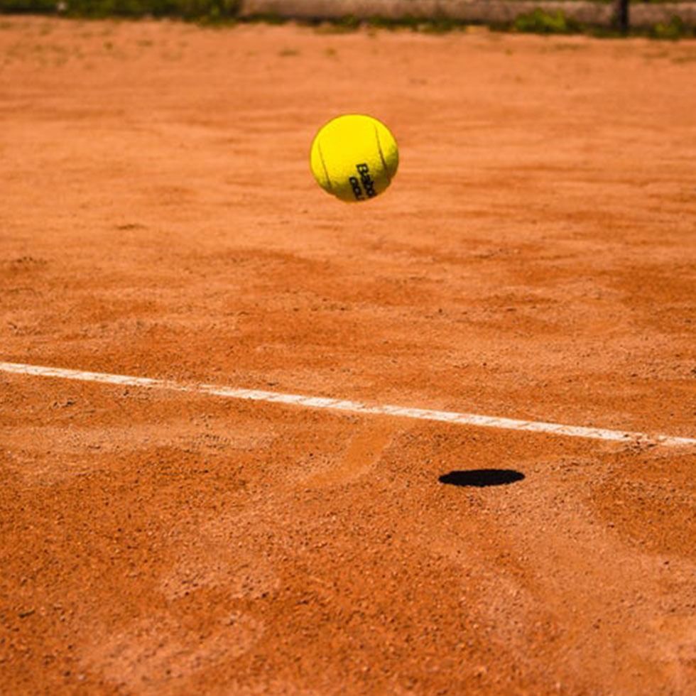A tennis ball is hitting the court near Falkensteiner Hotels