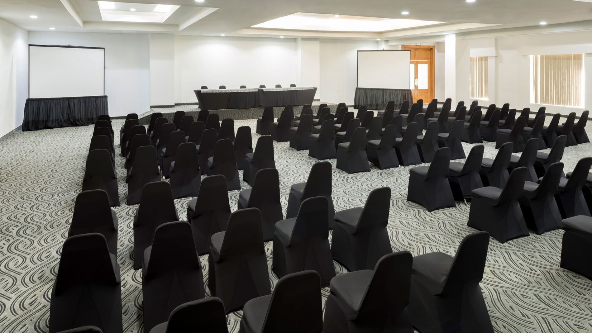 Sala de eventos Bangkok en Real Inn Mexicali con sillas y proyectores.
