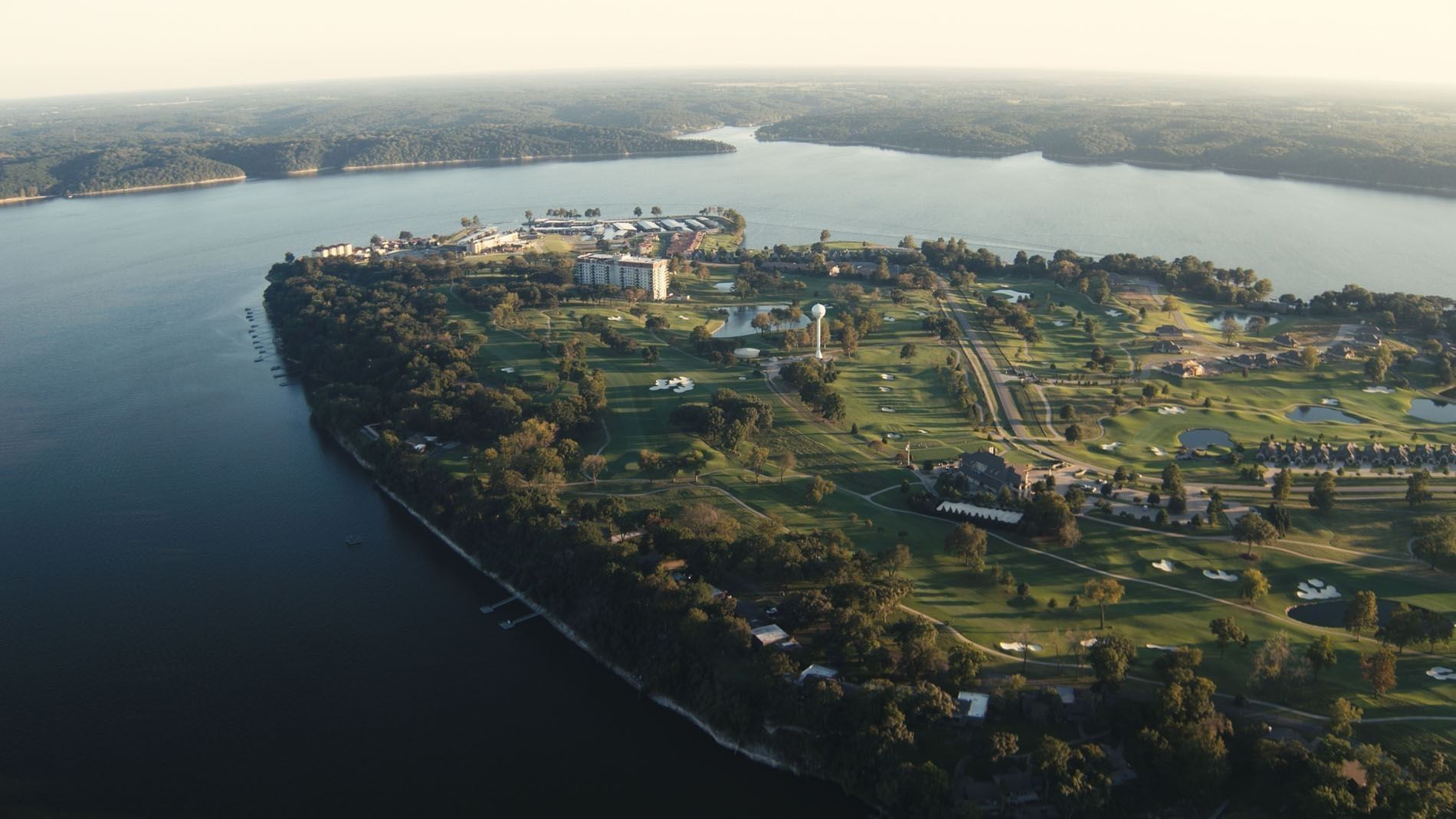 Panoramic aerial view of a resort peninsula surrounded by a lake and green forests at Shangri-La Resort and Golf Club