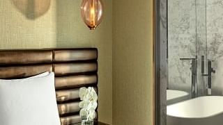 Bed with brown tufted headboard and nightstand in the Premier Suite with Panoramic View at Paramount Hotel Dubai