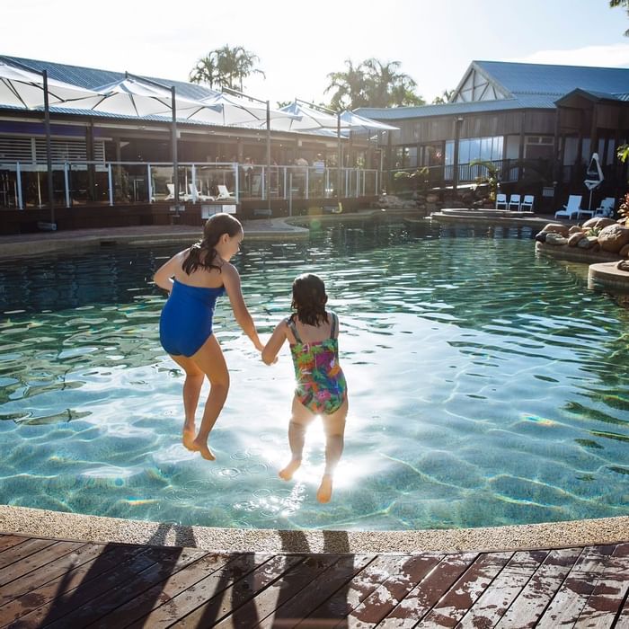 Two children jumping into the outdoor sunny pool at Mercure Hotel Townsville