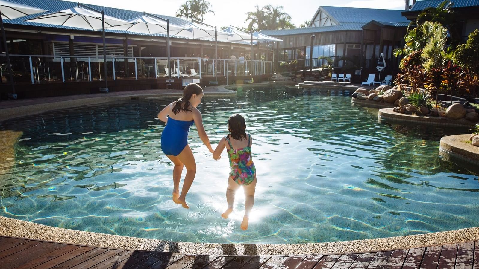 Two children jumping into the outdoor sunny pool at Mercure Hotel Townsville
