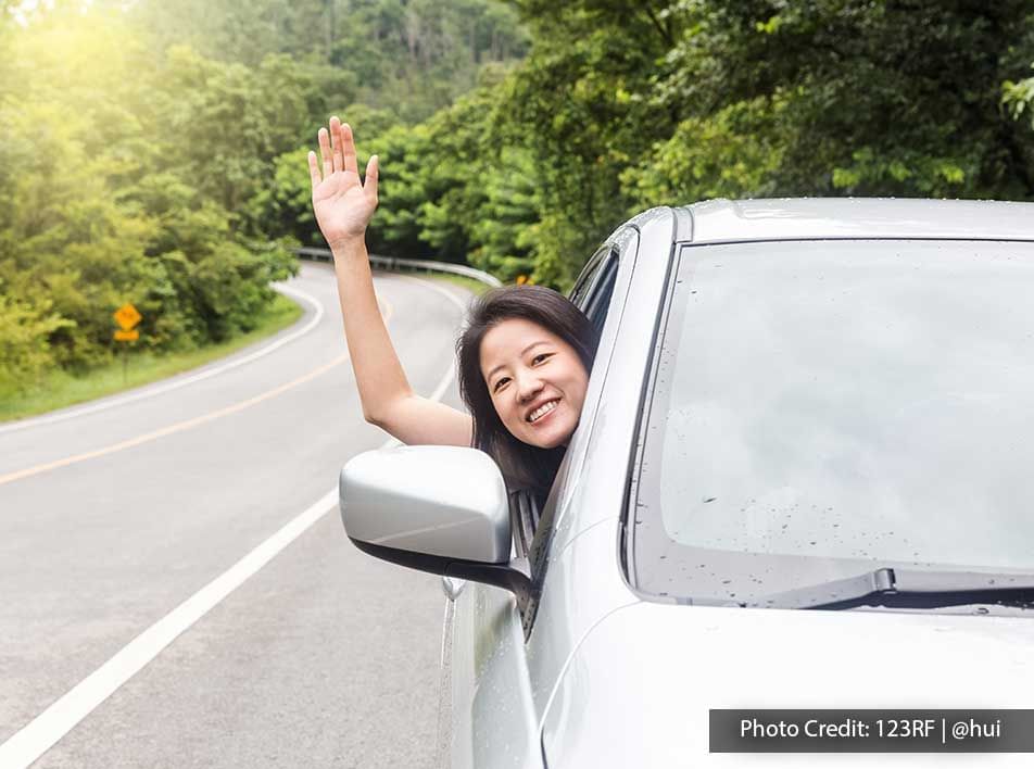 A woman was raising her hand through the car window during her road trip - Lexis Suites Penang