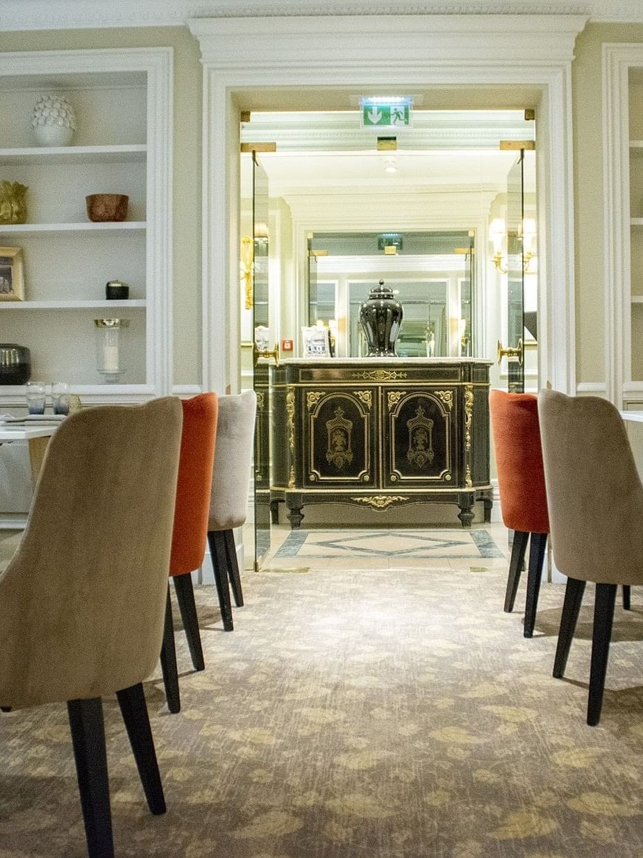 Dining table set with chairs, placed by recessed shelves and a dark cabinet in Le Céladon near Hotel Westminster Paris