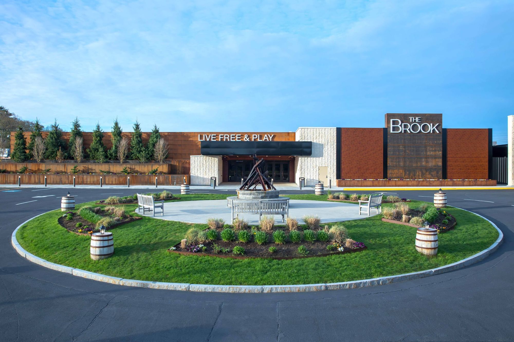 Exterior view of modern gaming building with Live Free and Play sign at driveway entrance venue at The Brook