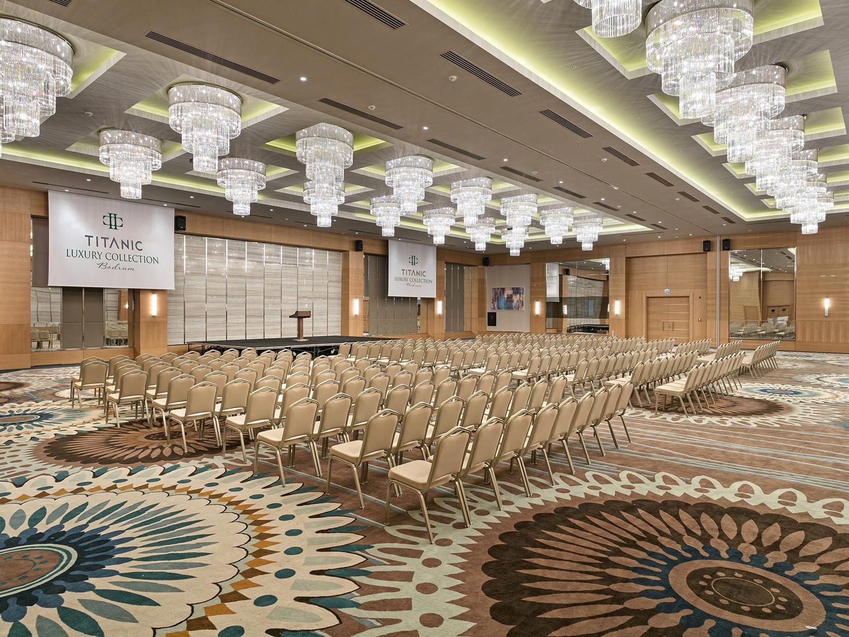 A luxurious conference hall with grand chandeliers and elegant seating at Titanic Luxury Collection Bodrum.