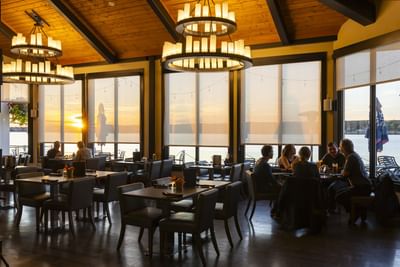 Dining tables by a window wall under tiered chandeliers at Rodd Miramichi River, a top choice place to eat in Miramichi