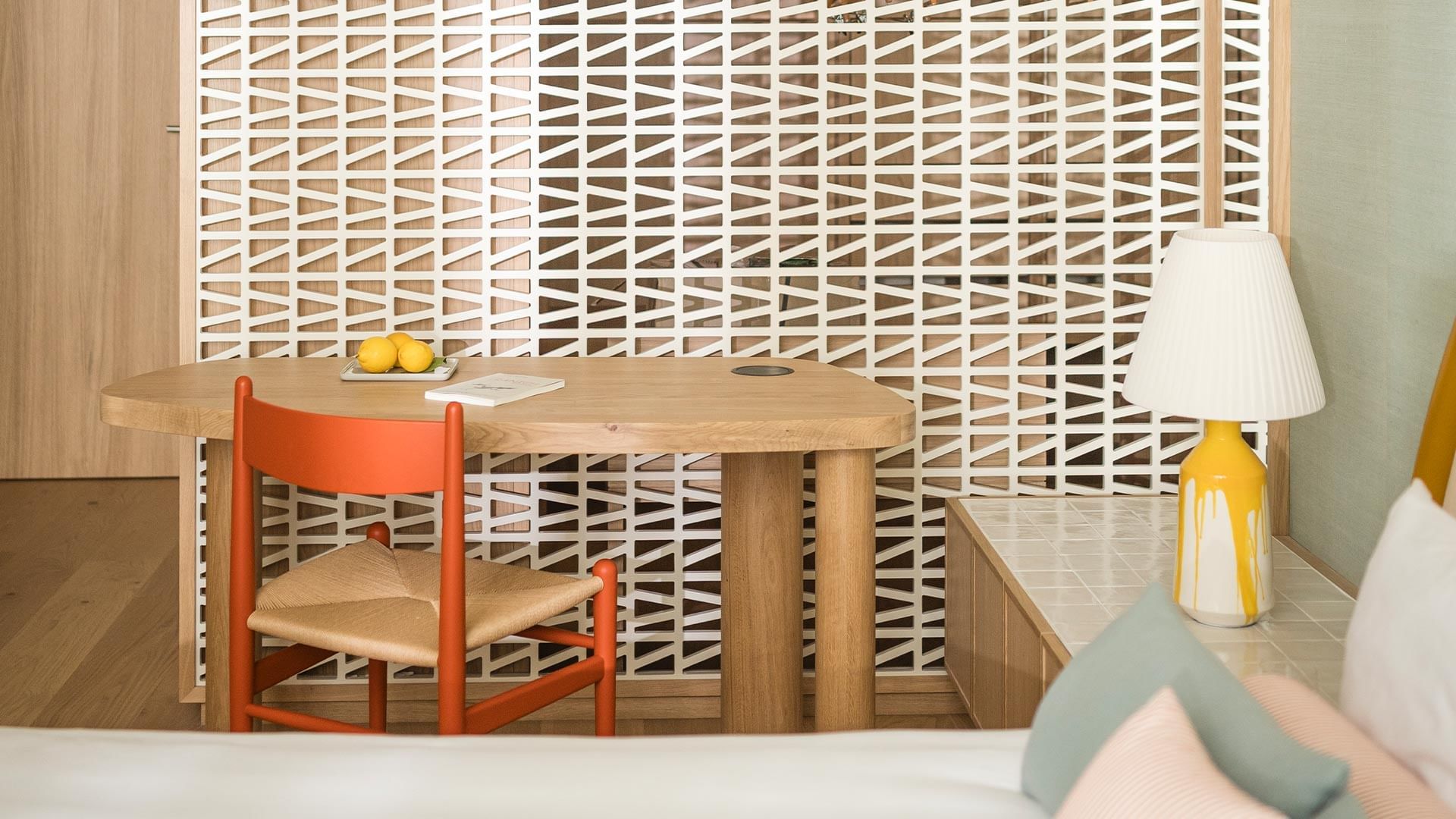 Modern room with a desk, chair, lemons, book, yellow lamp, and a geometric wall panel.