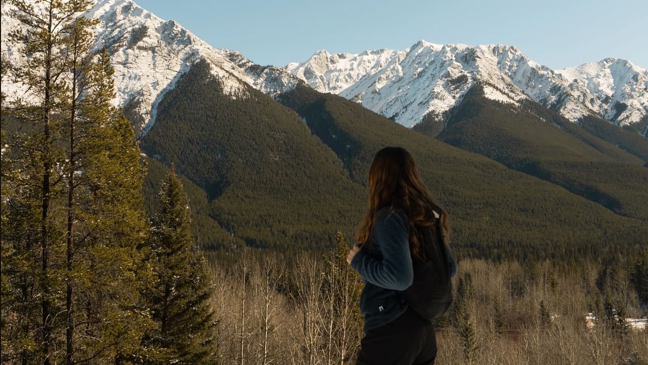 A person admires the mountains while on a hike in Banff.