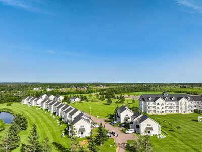 Aerial view of white villa cottages lining a vibrant green golf course lawn at Rodd Crowbush Golf & Beach Resort