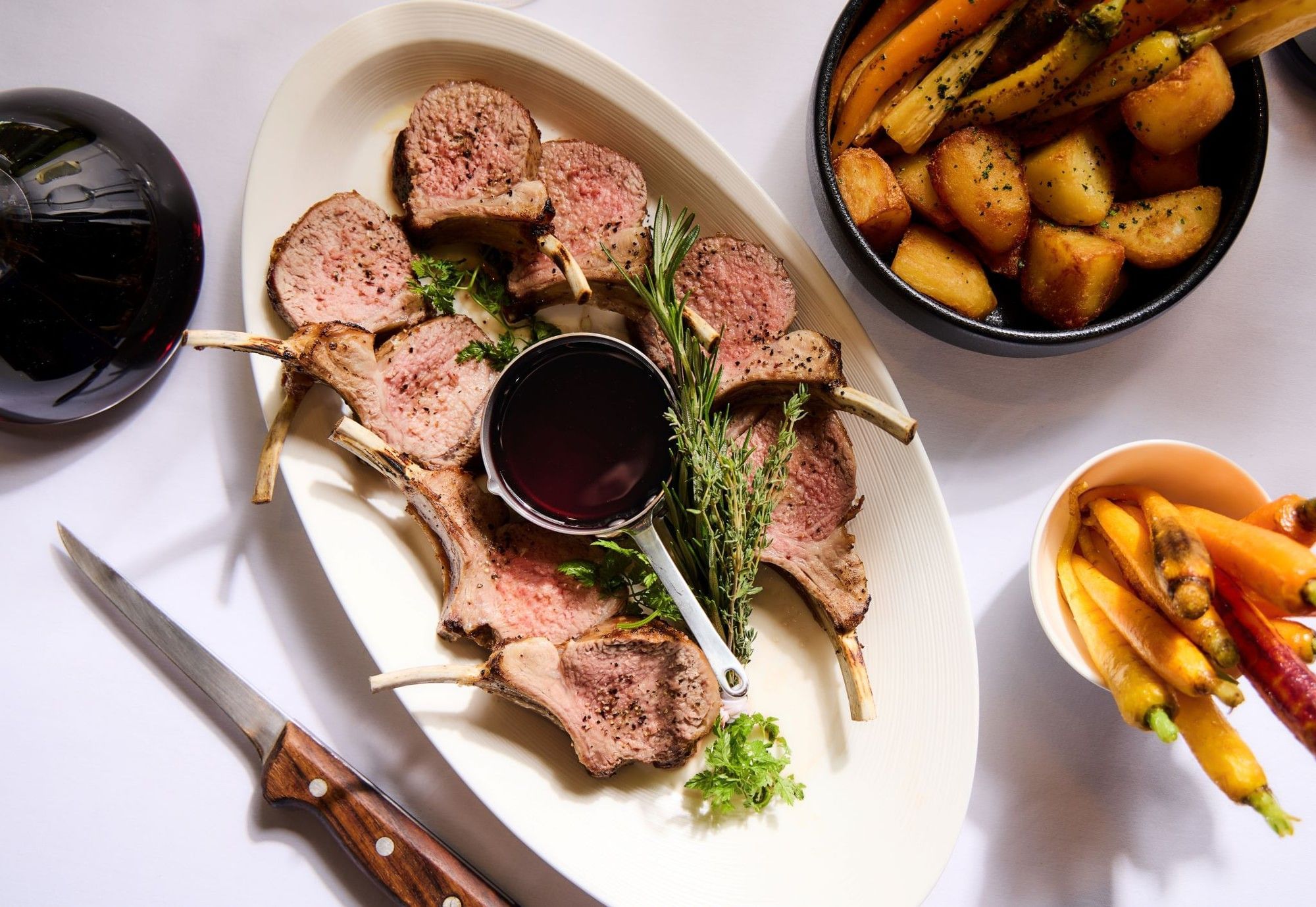 Rack of lamb with rosemary and a rich red wine sauce, served with roasted vegetables in Sunday Roast at The Londoner Hotel