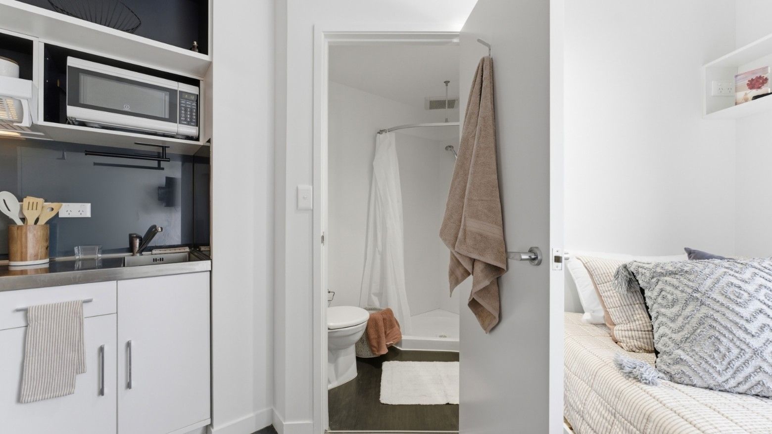 Modern compact suite with kitchenette, bathroom, and cozy bed at UniLodge Auckland City.