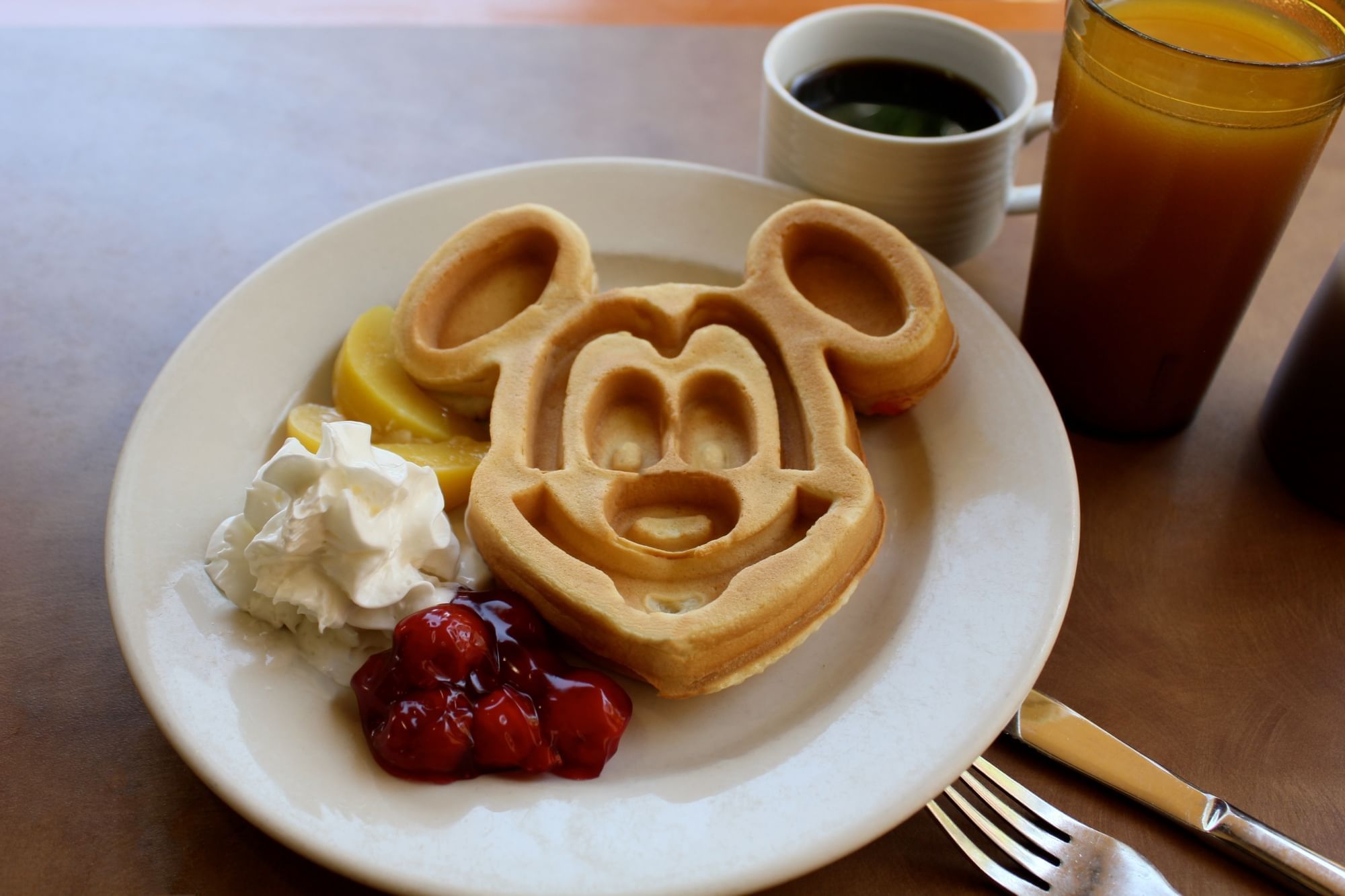 Mickey Mouse-shaped waffle on a plate with whipped cream and berries at Rosen Inn Lake Buena Vista.