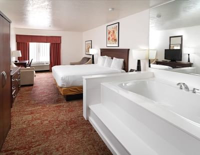 Comfy bed and working table in King Jetted Tub Suite at Crystal Inn Hotel & Suites