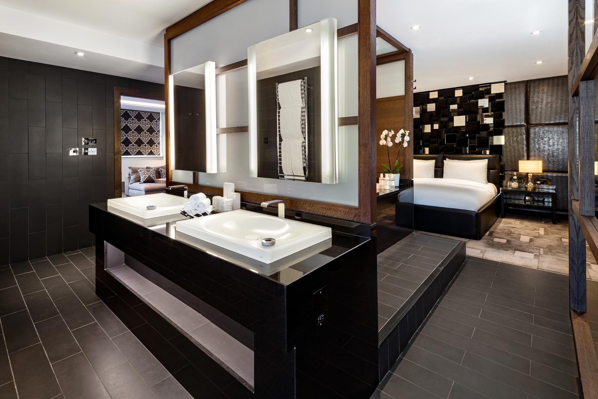 Open-plan bedroom and bathroom featuring sleek design and dual sinks at The May Fair Hotel