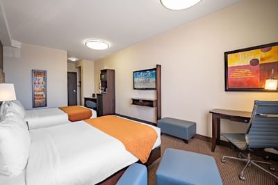 Two beds, work desk, and TV in a room at Acclaim Hotel Calgary