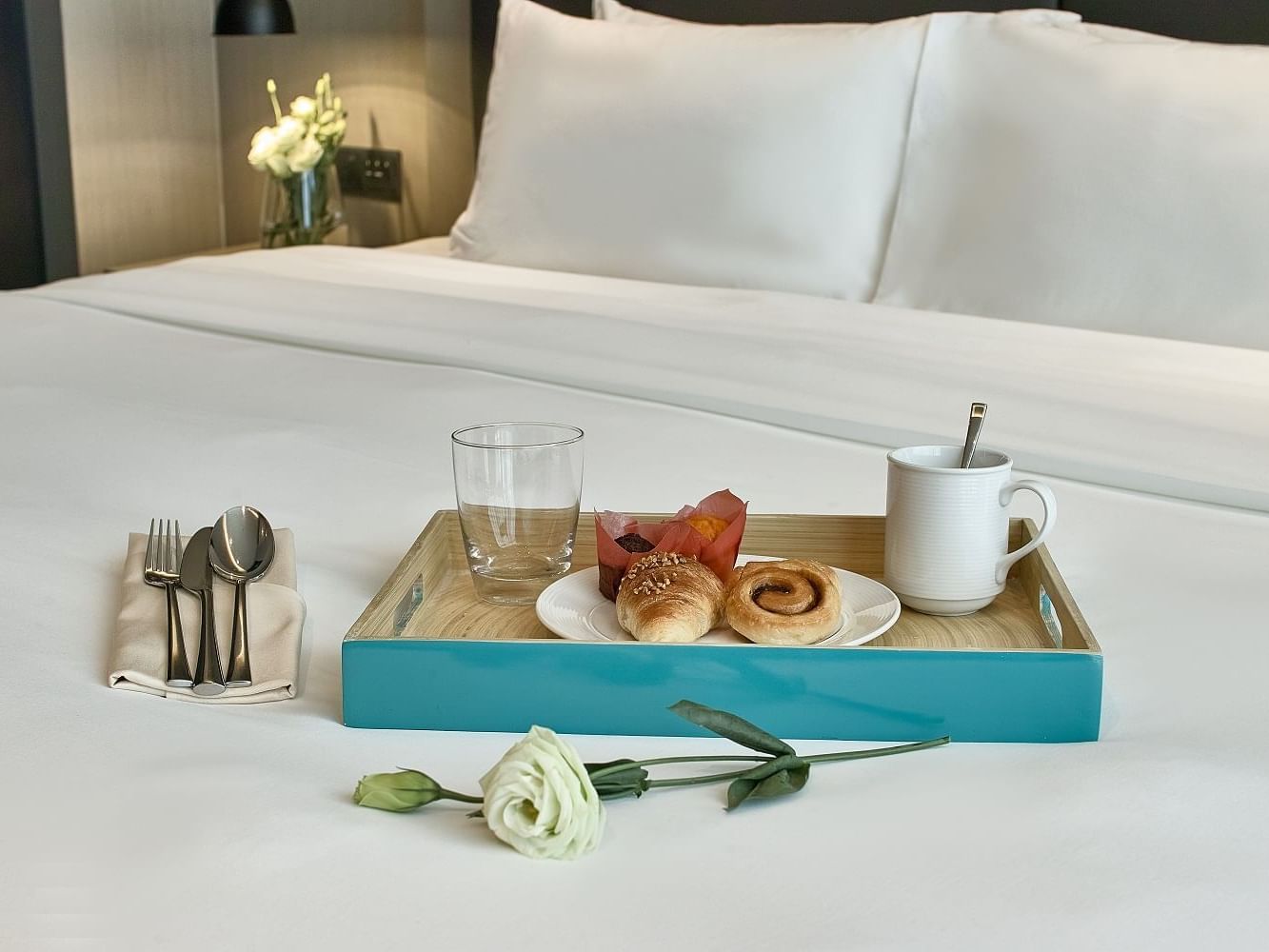 A tray with breakfast items on a bed at VE Hotel & Residence