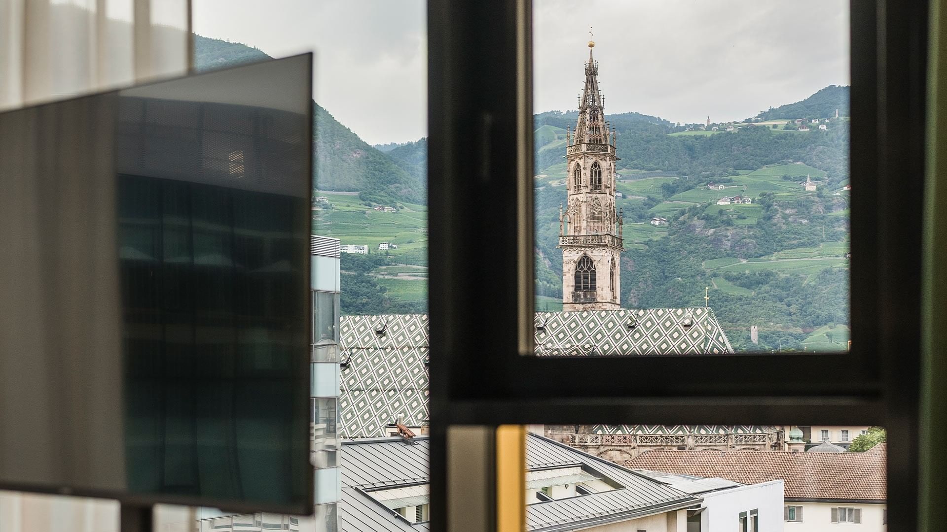 Scenic view of Bolzano cityscape and mountains from window at Falkensteiner Hotel Bozen WaltherPark.
